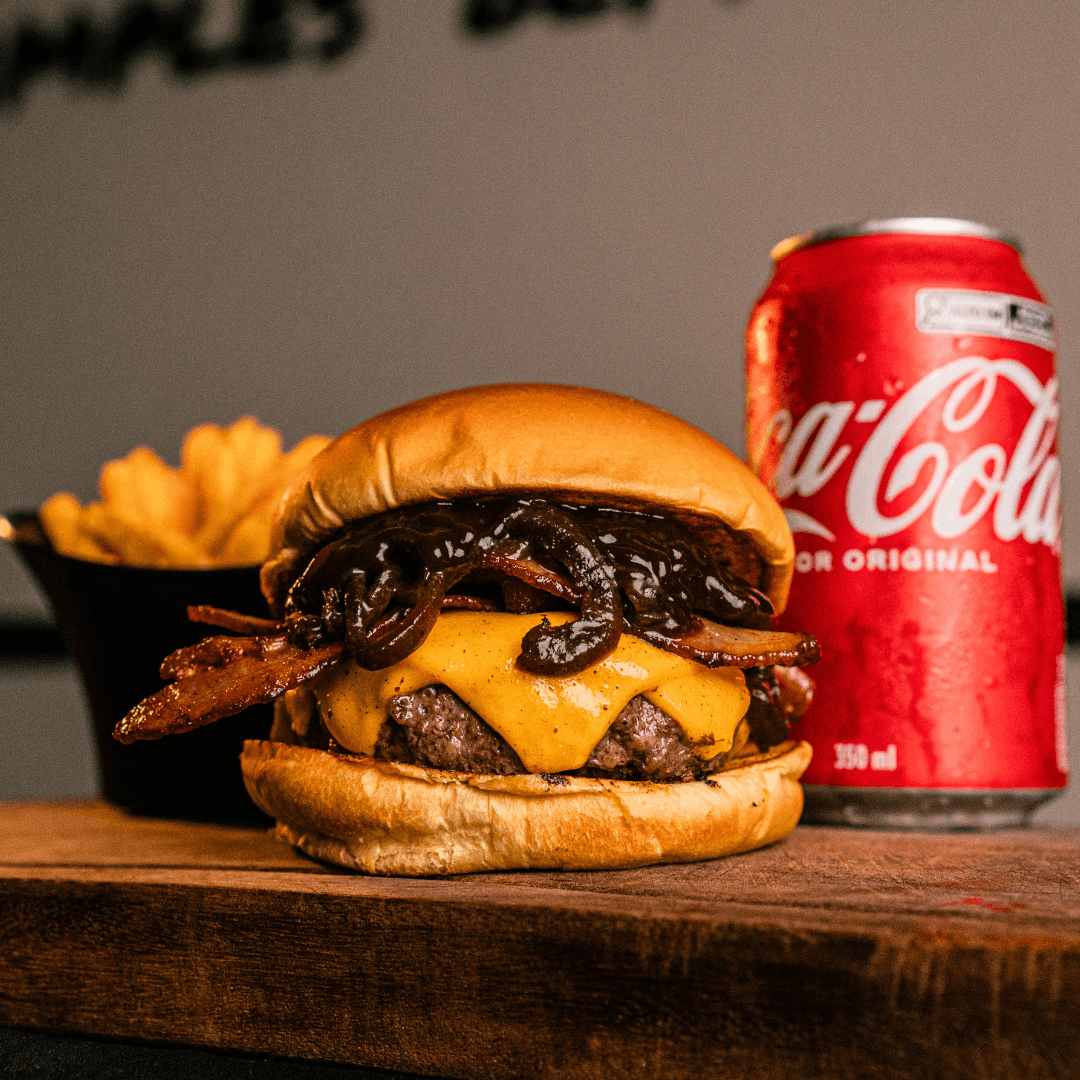 Hambúrguer com bacon, cheddar e cebola caramelizada, acompanhado de fritas, na Co.Burg